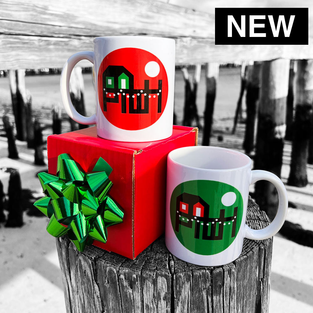 Two mugs with Provincetown Wharf Holiday designs on a wooden post and red box with a green bow.