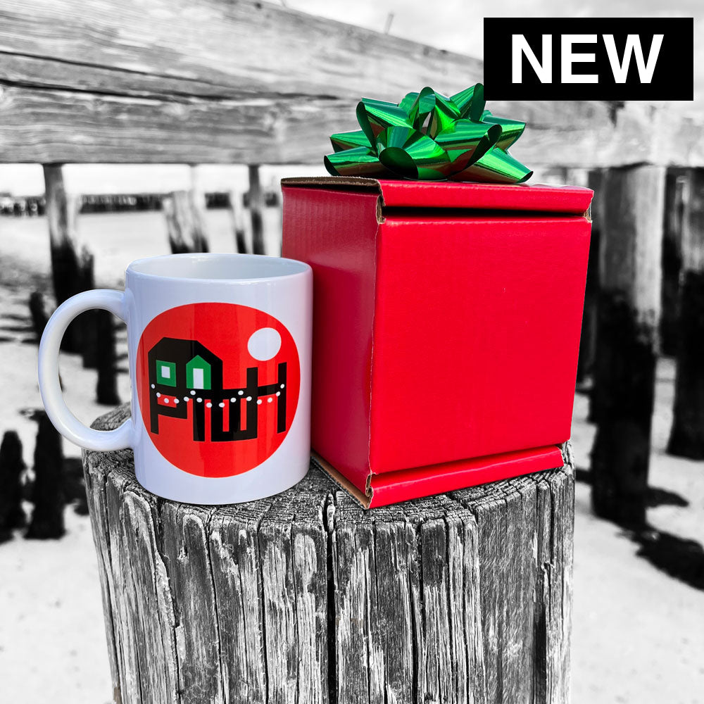 White Provincetown mug with red design on a wooden post, next to a red gift box with a green bow.